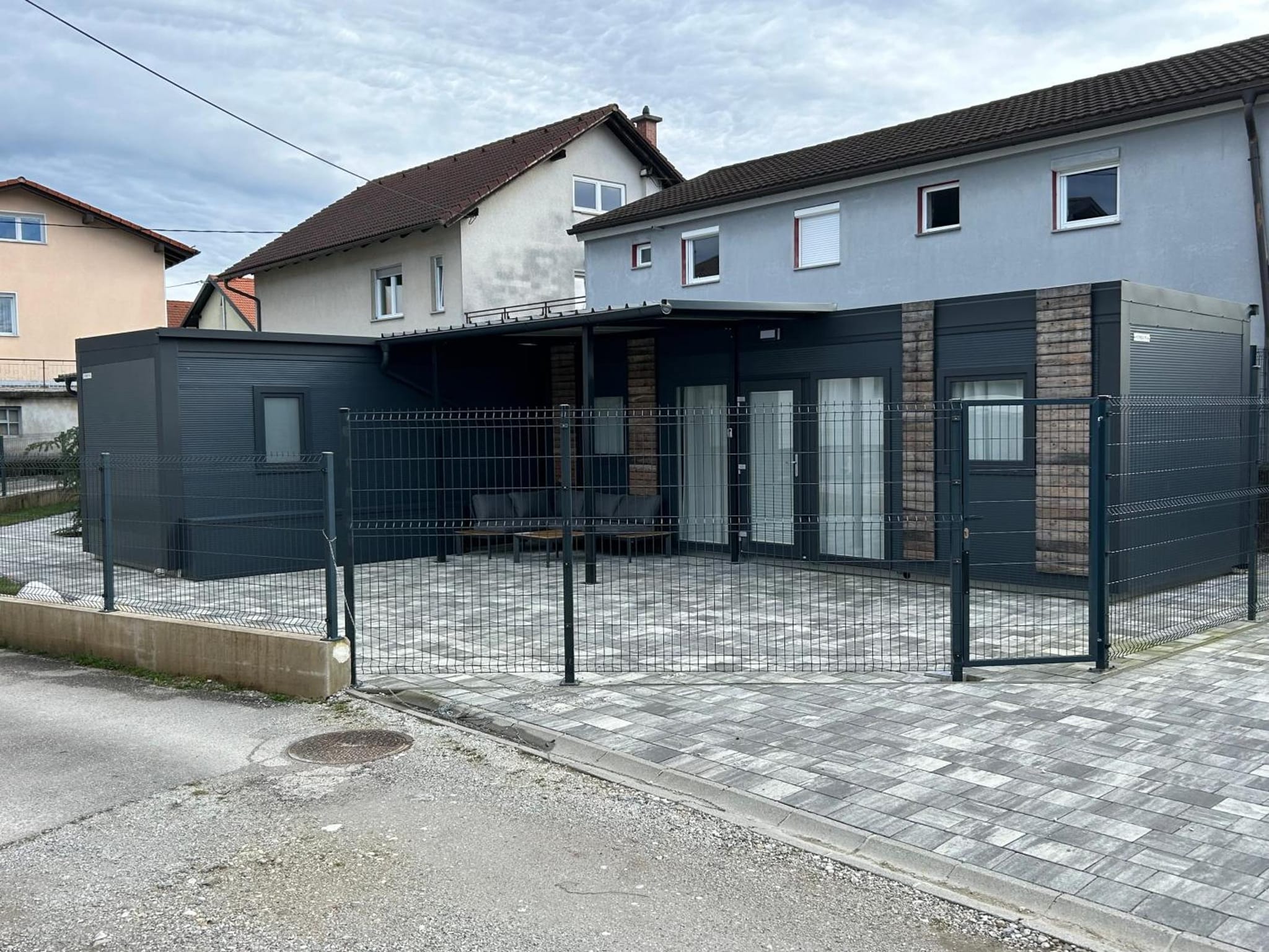 Tri tiny hiške, videne s ceste, s sosednjo hišo v ozadju